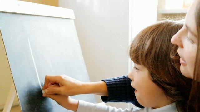 boy with his mother studying letters on a blackboard