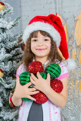 Little girl in Santa hat holding Christmas decoration in hands