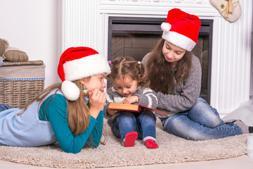 Elder sisters reading a Christmas story his little sister.