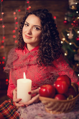 Cute woman with candle next to christmas tree