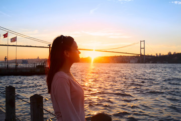 Young girl on background of Bosphorus bridge and sunset