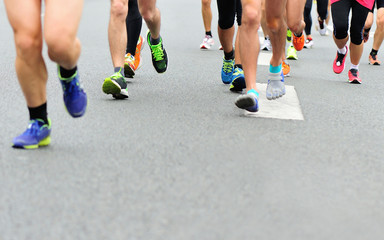 Unidentified marathon athletes legs running on city road 