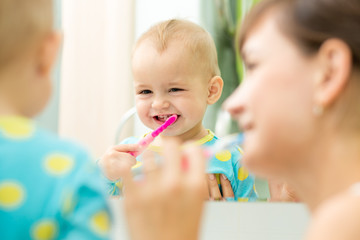 mother and kid look at mirror during teeth brushing - 74434918