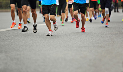 Unidentified marathon athletes legs running on city road 