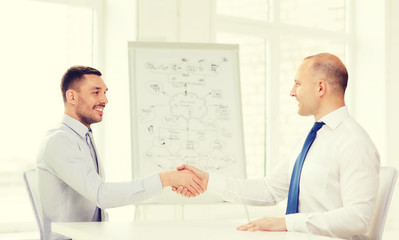 Naklejka na ściany i meble two smiling businessmen shaking hands in office