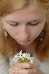 Red-haired girl with freckles looking at white flowers