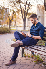 Obraz premium A smart young businessman with a beard using a tablet computer