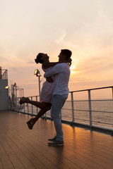 happy young couple enjoying a romantic sunset on cruise