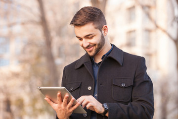 A smart young businessman with a beard using a tablet computer