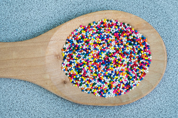 Sugar sprinkle dots or sugar balls on a wooden spoon