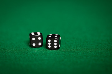 close up of black dice on green casino table