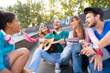 Young people playing guitar at the skatepark