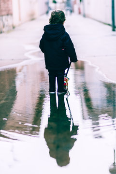 real portrait of a child playing in the street on a rainy day