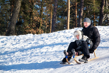 Father and son sliding in the snow.