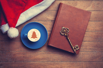 Cappuccino with key and book on wooden table.