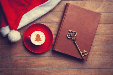 Cappuccino with key and book on wooden table.