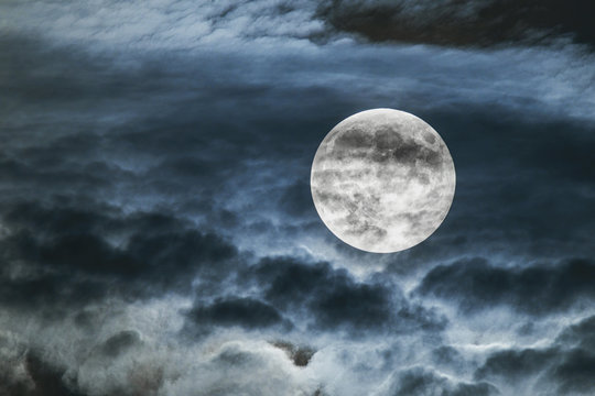 Full Moon behind faint clouds