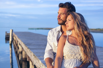 man embracing his woman from behind on seaside background under