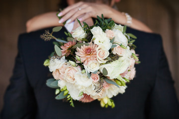 Bride with a bouquet in the hands of the hugging groom