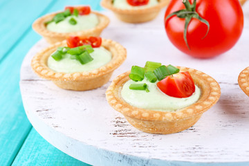 Fototapeta na wymiar Tartlets with greens and vegetables with sauce on tray on table