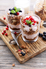 Healthy layered dessert with muesli and berries on table