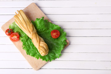Smoked braided cheese on wooden table