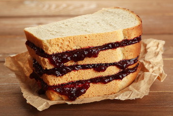 Tasty sandwich with jam on wooden table