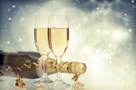Glasses with champagne and bottle over holiday background