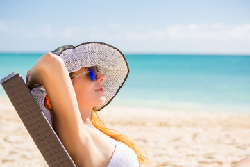 Young woman with sun hat enjoying sea view laying on chair