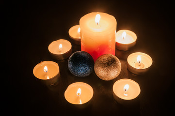 Small candles around a bigger candle and two Christmas globes