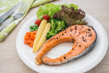 Grilled salmon steak with vegetables on plate