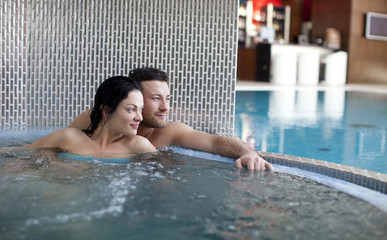 Couple relaxing in jacuzzi of spa center  - obrazy, fototapety, plakaty