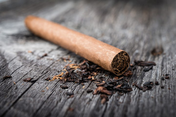 brown cigar on grey wooden table with tobacco leaves.