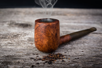 tobacco pipe  with smoke in wooden grey table.