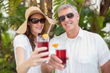 Holidaying couple toasting with cocktails