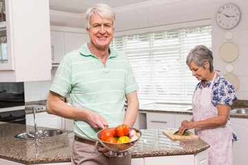 Senior man showing colander of vegetables