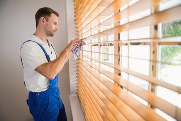 Handyman cleaning blinds with a towel