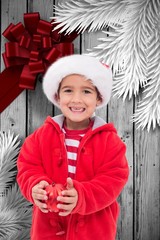 Composite image of cute little boy holding bauble