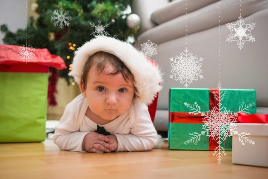 Composite image of cute baby boy lying on floor at christmas