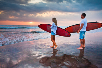 Couple of surfers walking on coast in Indonesia