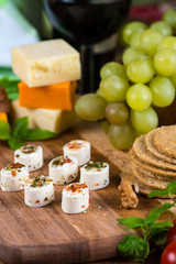 Selection of party cheese snacks with herbs on board