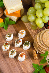 Selection of party cheese snacks with herbs on board