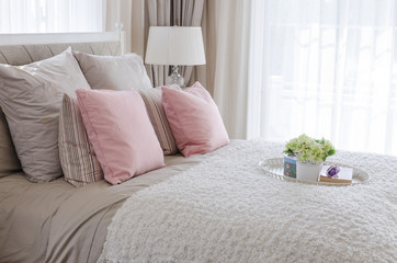 pink pillows on bed with white tray of flower