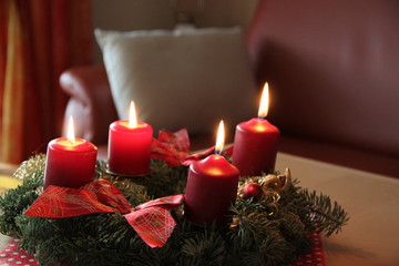 Adventskranz mit brennenden Kerzen im Wohnzimmer