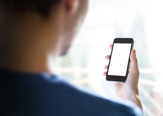 Rear view of young man using smartphone with blank screen – over-the-shoulder mockup