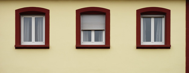 Fototapeta na wymiar Drei moderne Kunststofffenster in Altbaufassade mit Rollläden