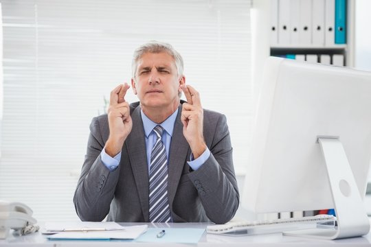 Wishing businessman crossing his fingers