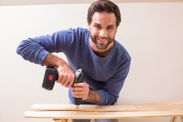 Casual man drilling hole in plank