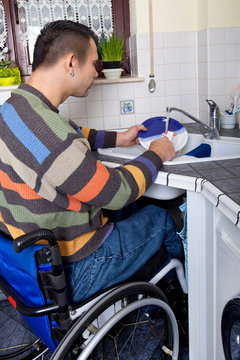 Rollstuhlfahrer beim Geschirr spülen