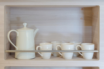 Fototapeta na wymiar teapot and cups on wooden shelf